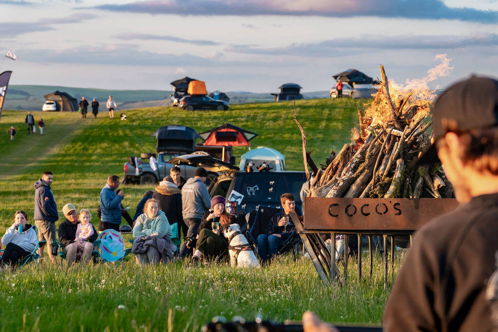 A group of TentBoxers gathered in a field around the communal campfire