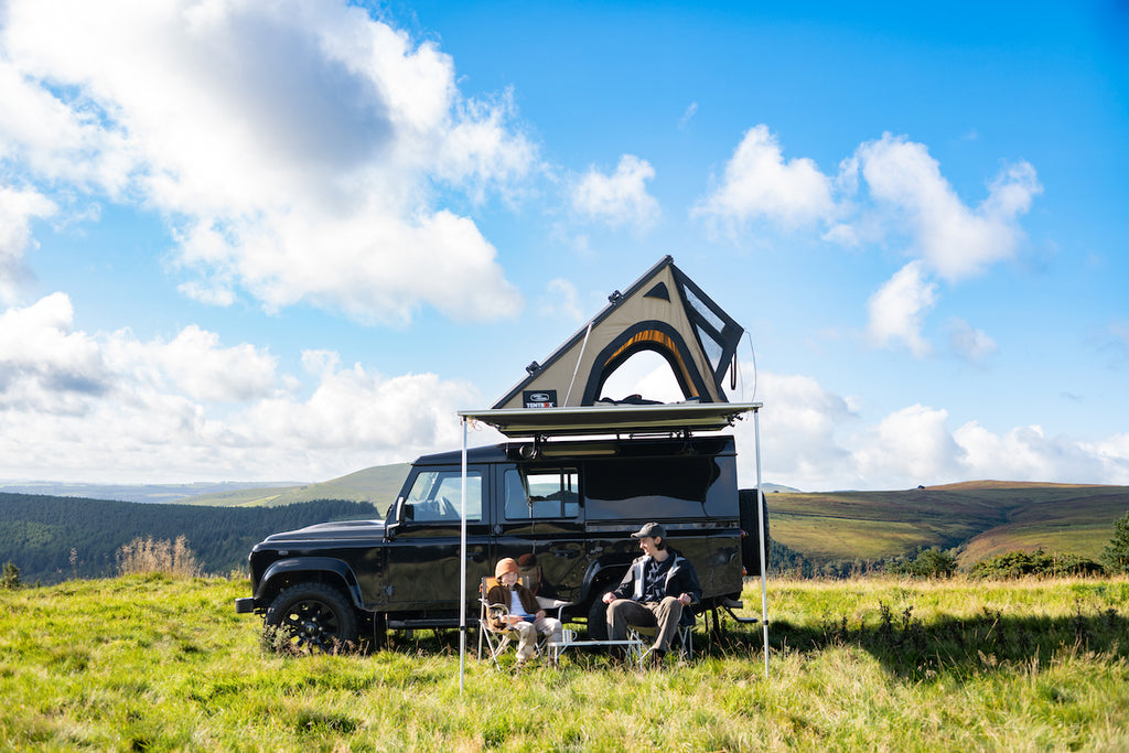 A Land Rover Defender with a special edition TentBox Cargo in the middle of a green field