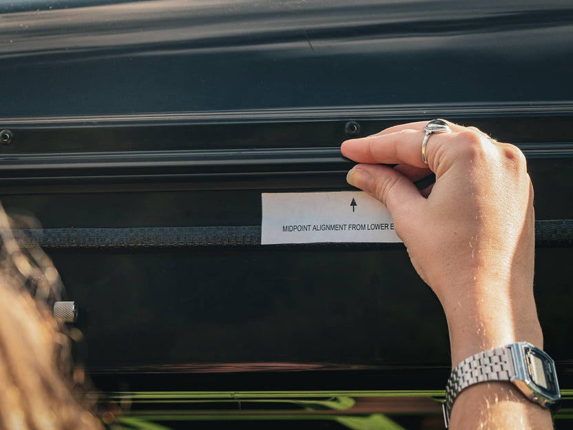 Close up image of woman installing the Adaptor Kit on the TentBox Classic 1.0 in order to fit the Living Pod