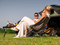 People sat out on TentBox Camping Chairs enjoying themselves in the sun, with a grey camping chair in the foreground