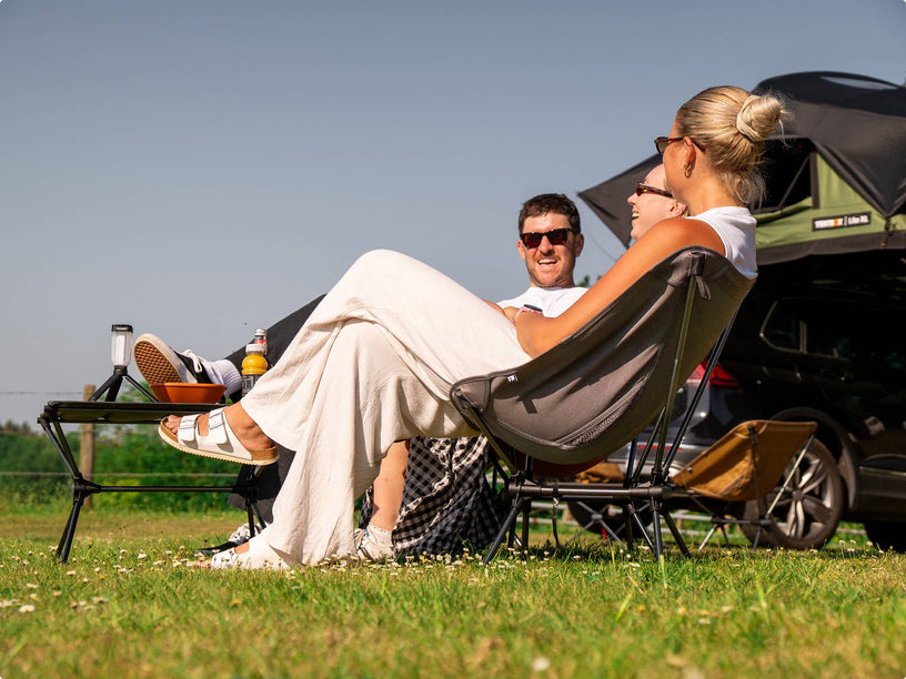 People sat out on TentBox Camping Chairs enjoying themselves in the sun, with a grey camping chair in the foreground