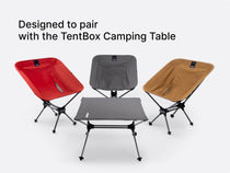 An image showing all three colours of the TentBox Camping Chair - red, grey and khaki - complete with a TentBox Camping Table in front. 