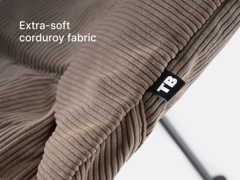 A close-up of the TentBox Camping Chair cushion in mustard showing the abbreviated "TB" logo and overlay text saying "premium corduroy warmth"