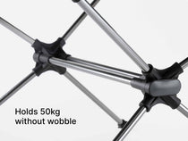 Close-up of a TentBox Camping Table with black and grey connector joints and silver poles, with text reading 'Holds 50kg without wobble' on a light grey background.