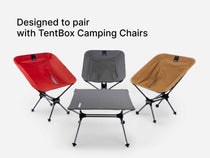 Three TentBox Camping Chairs in red, grey, and khaki, arranged around a matching TentBox Camping Table on a light grey background, with the text 'Designed to pair with TentBox Camping Chairs' at the top.