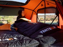 TentBox Sleeping Bag - woman lying in sleeping back looking out of the window of a roof tent