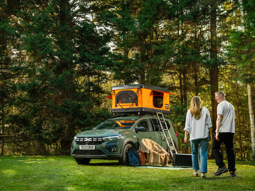 Two people returning to their TentBox Classic roof tent at their campsite 