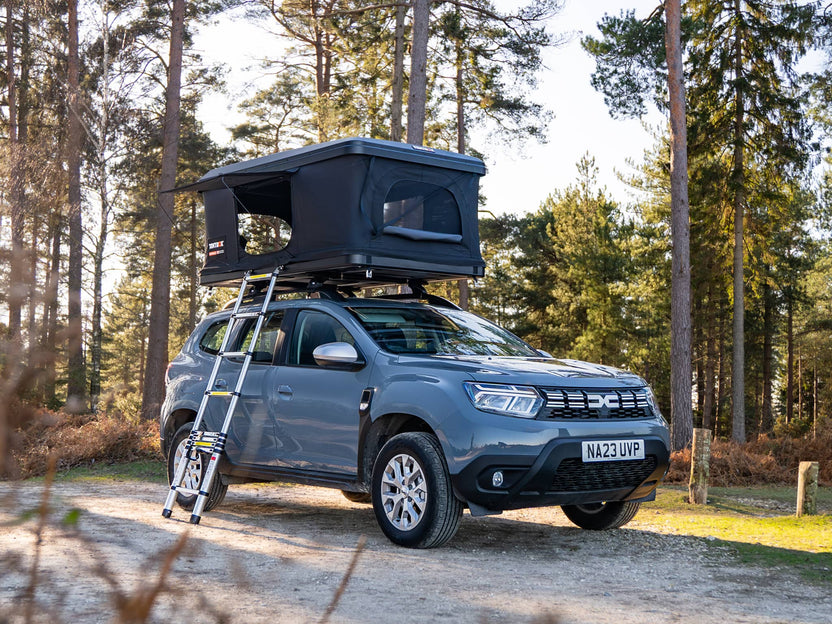 The TentBox Classic roof tent on the roof of a Dacia Duster in a forest camping spot