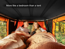 An internal shot of the TentBox Classic roof tent showing two people inside with the hardshell roof - more like a bedroom than a tent.. 