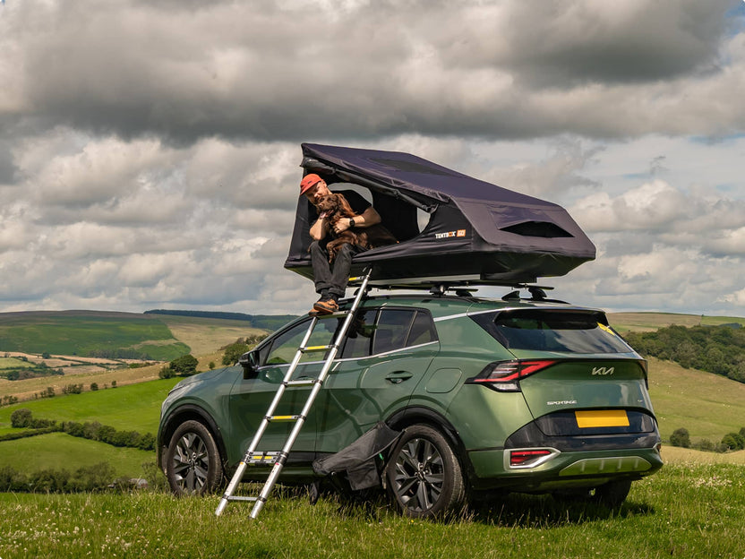 The TentBox GO roof tent on a Kia Sportage being used by a man with a dog. 
