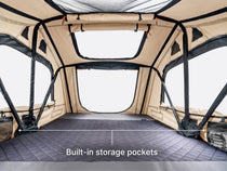 The interior of a TentBox Lite rooftop tent in limited edition clay colour,  showing built-in storage pockets on both sides and a text overlay that reads 'Built-in storage pockets'.