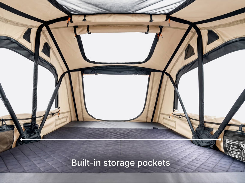 The interior of a TentBox Lite rooftop tent in limited edition clay colour,  showing built-in storage pockets on both sides and a text overlay that reads 'Built-in storage pockets'.