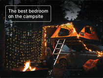 TentBox Lite 2.0 roof tent glowing with fairy lights at night, creating a cosy and inviting camping bedroom