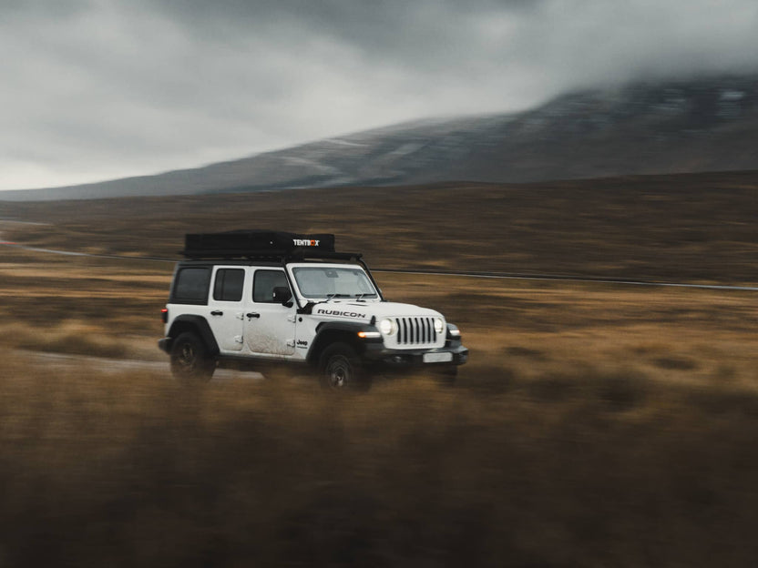 Driving through the Scottish highlands with the TentBox Lite XL mounted on top of a Jeep Wrangler.