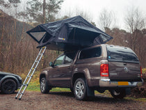 Black TentBox Lite 1.0 roof tent installed onto a large Volkswagen Amorak truck, set-up for camping