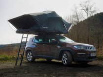 The TentBox Lite XL roof tent on the roof of an SUV style vehicle in a forest setting