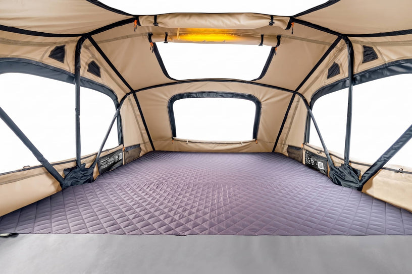 A spacious TentBox lite XL rooftop tent interior with a quilted purple floor mat, beige walls, and large window openings, photographed from inside the tent looking forward.