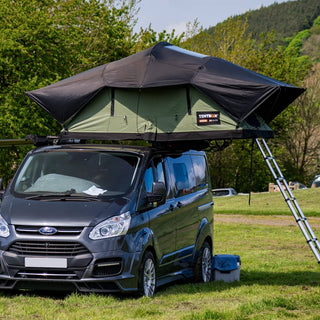 A TentBox LIte XL in Forest Green installed on a Ford van which is park at a campsite