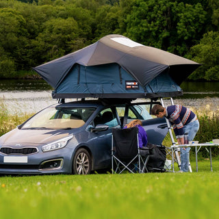 Couple enjoying their lakeside camp with their Slate Grey TentBox Lite 2.0 on top of their hatchback car