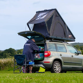 A man reaching for camping equipment in the back of his estate car with a Midnight Grey TentBox Cargo 2.0 installed