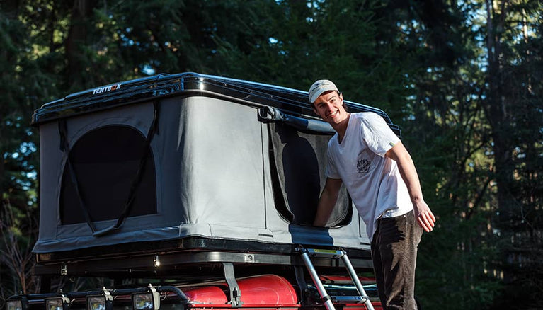 An adventurous man climbing up the ladder into a TentBox Classic roof tent