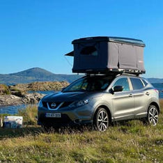 A camping spot with a TentBox Classic installed on the roof of a Nissan car