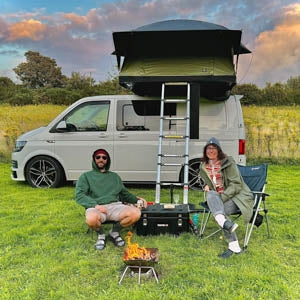 A couple enjoying time in the outdoors in front of their camper van with a TentBox Lite XL on top