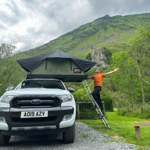 A man celebrating being outdoors with his Forest Green TentBox Lite 2.0 mounted on a white pick up truck