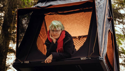 A woman enjoying her TentBox Cargo roof tent, with a cosy light in the background