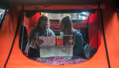 Two people sitting inside a TentBox Lite 1.0 whilst reading a map